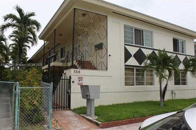 7315 Byron Avenue, Unit 17 Miami Beach, FL 33141 - Photo 1 of 10 a front view of a house with a garden and tree