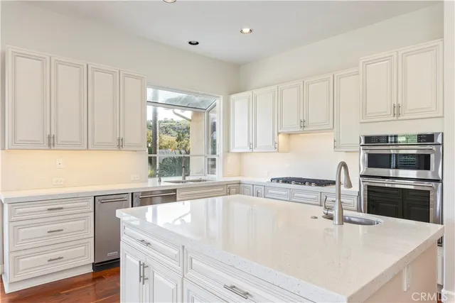 a kitchen with granite countertop white cabinets and stainless steel appliances