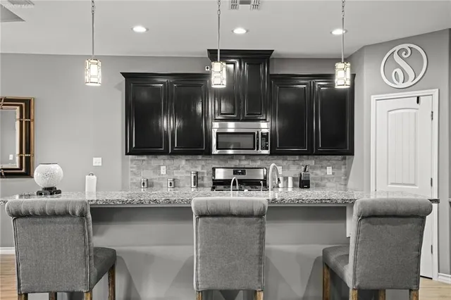 a kitchen with stainless steel appliances granite countertop a sink and a refrigerator