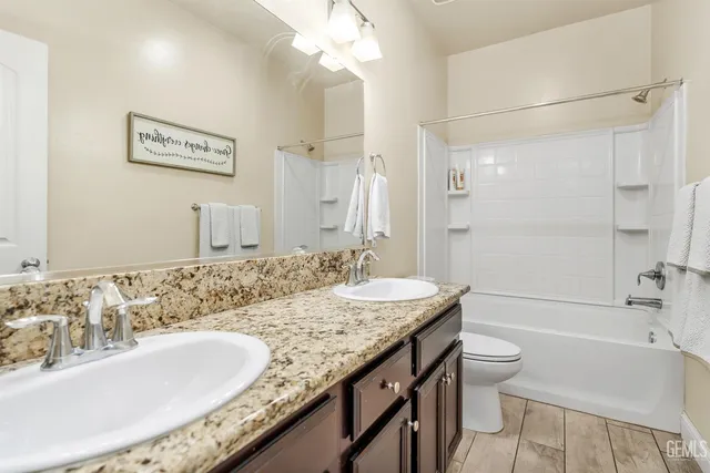 a bathroom with a granite countertop tub sink and mirror