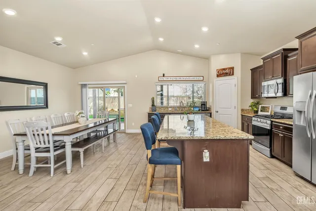 a dining hall with stainless steel appliances granite countertop a stove and a dining table with wooden floor