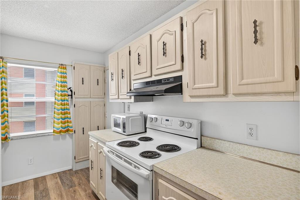 200 Pebble Beach Boulevard, Unit D406 Naples, FL 34113 - Photo 7 of 24 a kitchen with stainless steel appliances white cabinets and a stove top oven