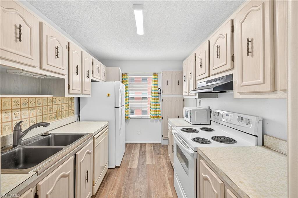 200 Pebble Beach Boulevard, Unit D406 Naples, FL 34113 - Photo 8 of 24 a kitchen with a sink a stove and cabinets