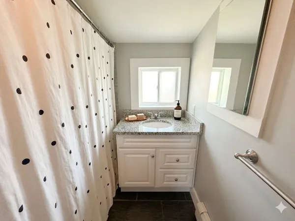a bathroom with a granite countertop sink a mirror and a shower