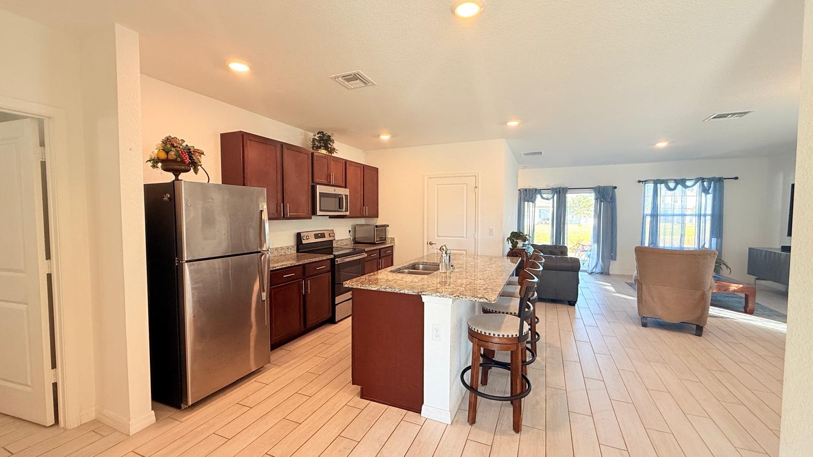 a kitchen with stainless steel appliances a refrigerator a stove top oven and a dining table with wooden floor