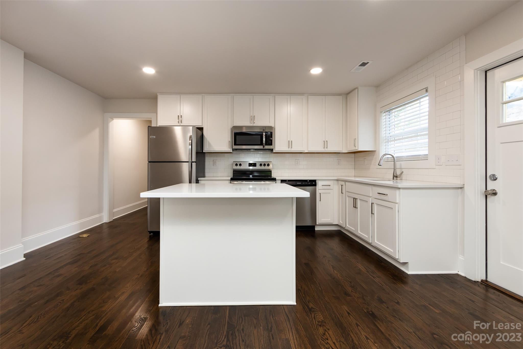 1704 Club Road, Unit A Charlotte, NC 28205 - Photo 13 of 35 a kitchen with a refrigerator a sink dishwasher a stove and white cabinets with wooden floor