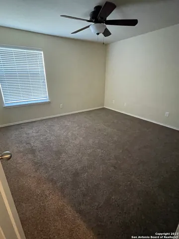 an empty room with a ceiling fan and a window