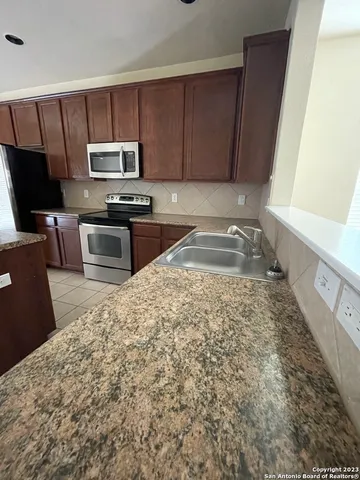 a kitchen with stainless steel appliances granite countertop a stove a sink and a microwave