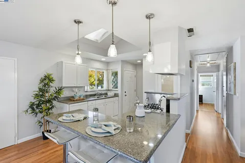 a view of a dining room and livingroom with furniture wooden floor a chandelier