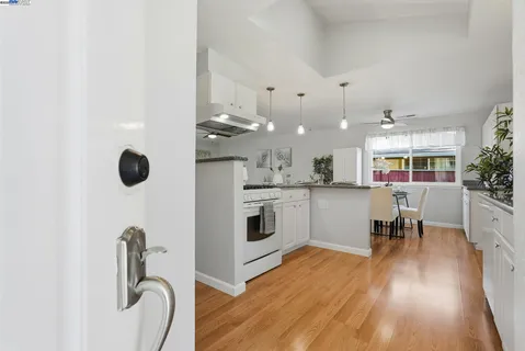 a kitchen with stainless steel appliances granite countertop a stove top oven a sink a dining table and chairs with wooden floor