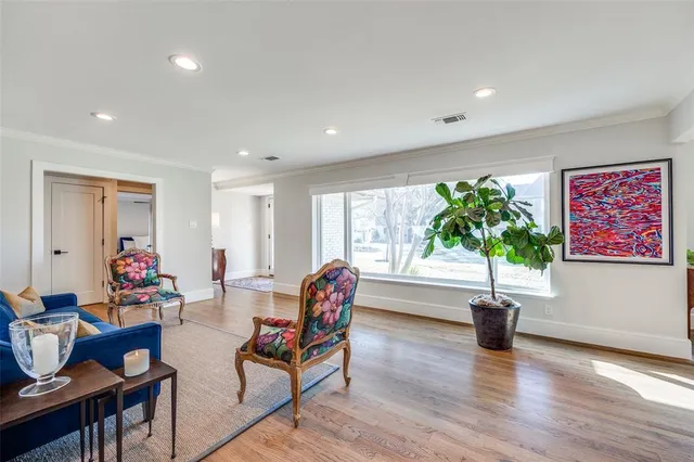 a living room with furniture a potted plant and open kitchen view