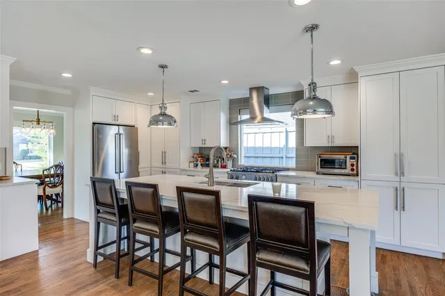 a kitchen with a dining table chairs wooden floor cabinets appliances and a center island