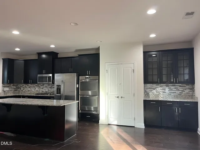 a kitchen with kitchen island granite countertop wooden cabinets and a refrigerator