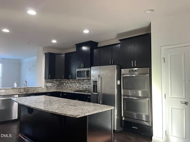 a kitchen with kitchen island a counter top space cabinets and stainless steel appliances