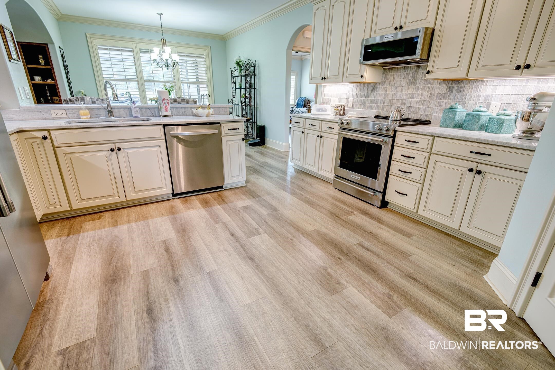 9357 Lakeview Drive Foley, AL 36535 - Photo 30 of 68 Gourmet kitchen featuring wood-finish flooring, white cabinetry, stainless steel appliances, a tile backsplash, and light-toned countertops