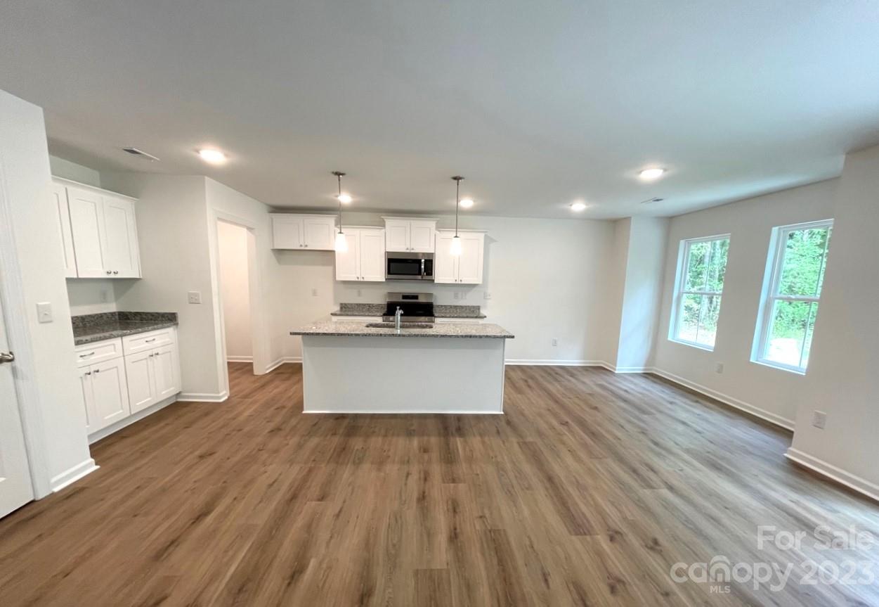 2173 Country Club Drive Lancaster, SC 29720 - Photo 6 of 18 a kitchen with granite countertop a stove a sink and white cabinets with wooden floor
