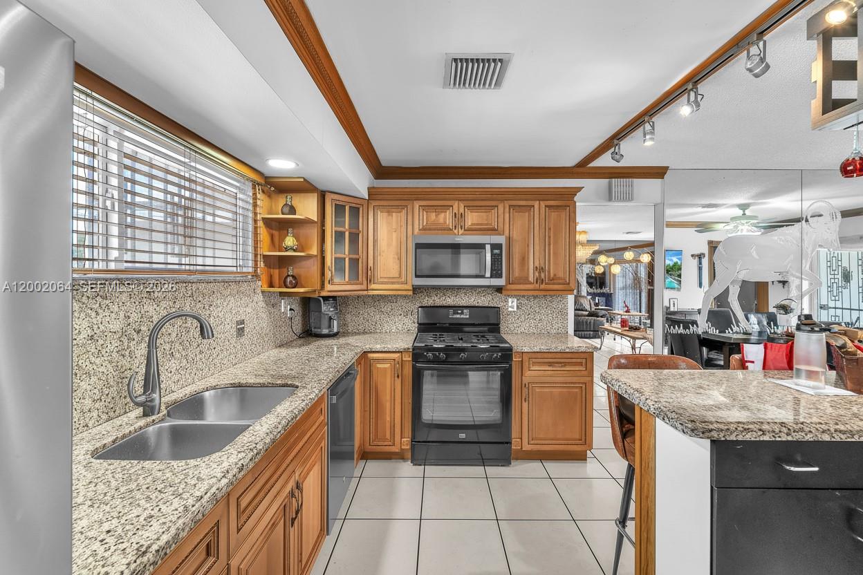 12310 Southwest 39th Terrace Miami, FL 33175 - Photo 12 of 42 a kitchen with stainless steel appliances granite countertop a sink stove and cabinets