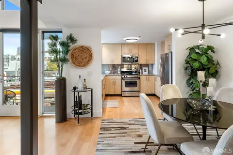 a living room with stainless steel appliances furniture a chandelier a rug and a large window