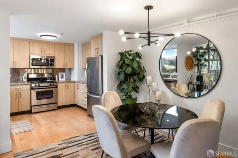 a kitchen with stainless steel appliances a dining table chairs and refrigerator