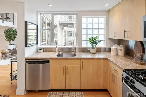 a kitchen with stainless steel appliances granite countertop a sink a stove and a window