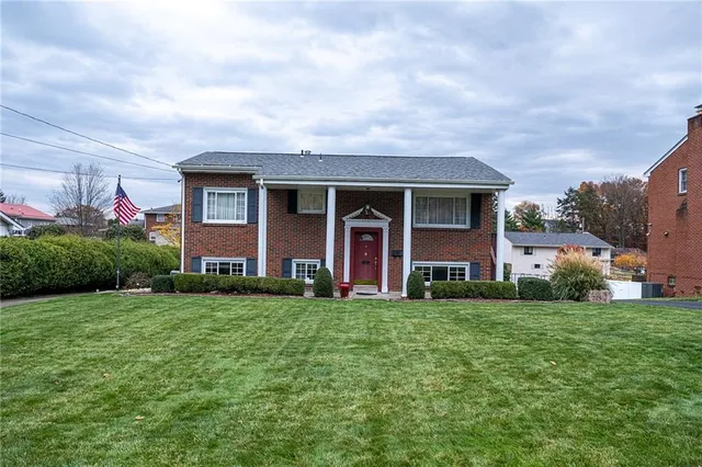 a view of a brick house with a big yard and potted plants