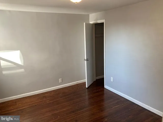 a view of an empty room with wooden floor and closet