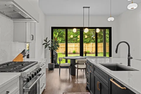 a kitchen with a stove a sink and a dining table with wooden floor