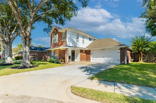 a view of a white house with a big yard and large tree