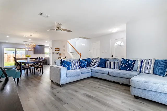 a living room with furniture kitchen view and a wooden floor