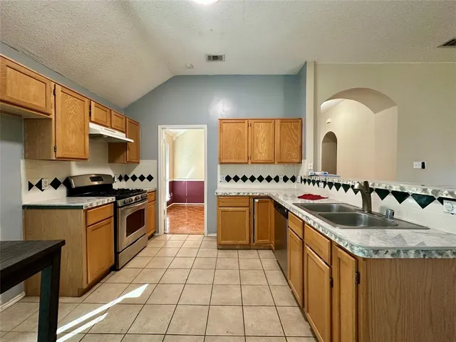 a kitchen with stainless steel appliances granite countertop a sink and a stove