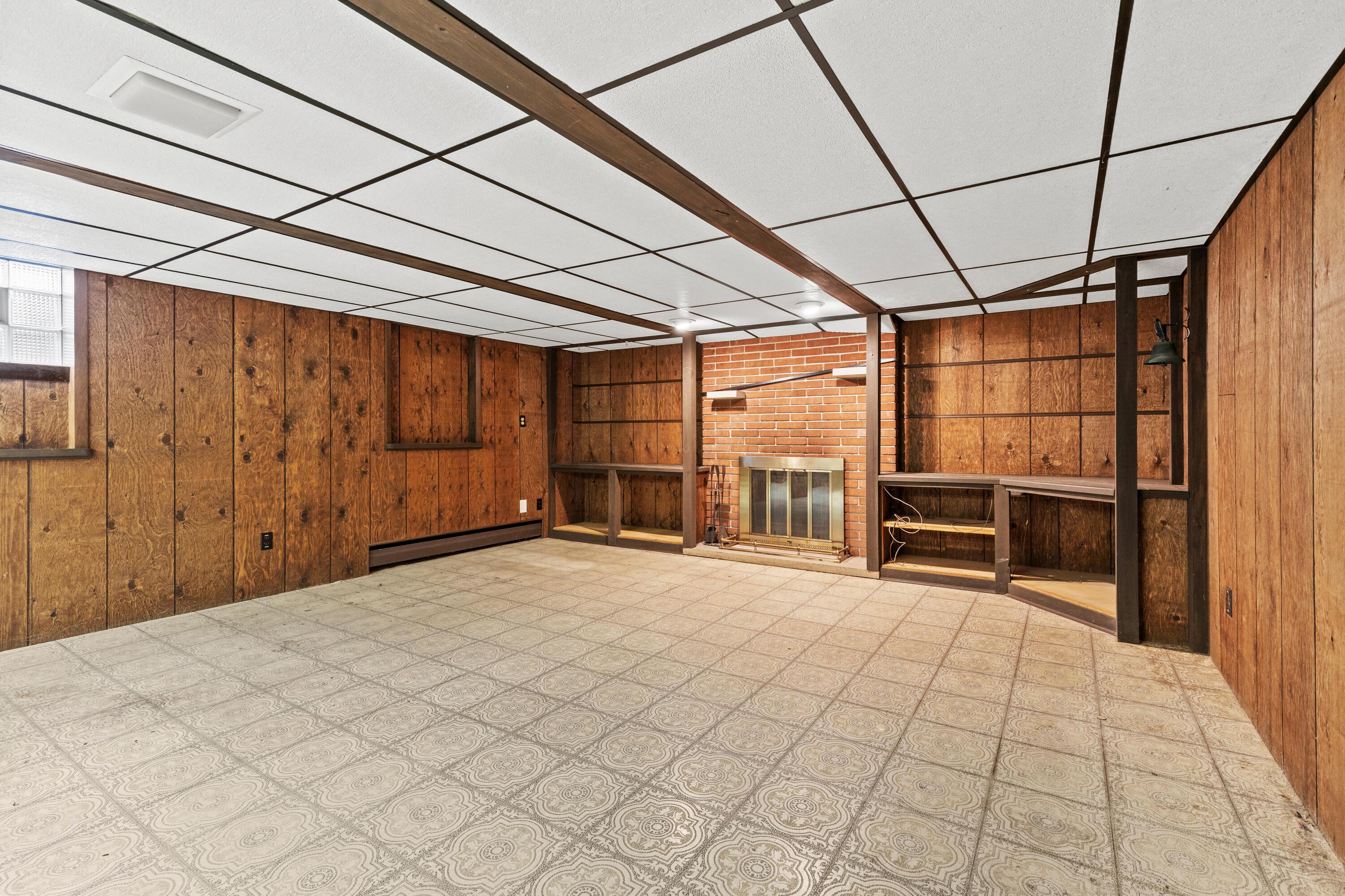 6982 Lee Road Westerville, OH 43081 - Photo 45 of 71 • Neutral vinyl flooring • Paneled walls • Acoustic ceiling tiles with fluorescent lighting • Can lighting • Woodburning, brick fireplace • Baseboard heat • (2) glass block windows • Built-in book shelves • Full wall of closets (cedar lined)