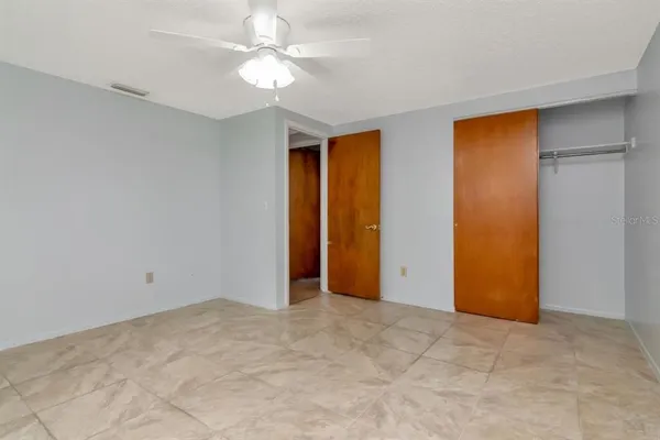 an empty room with closet and a ceiling fan