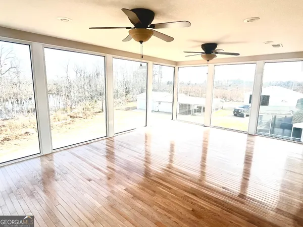 a view of an empty room with wooden floor and a large window