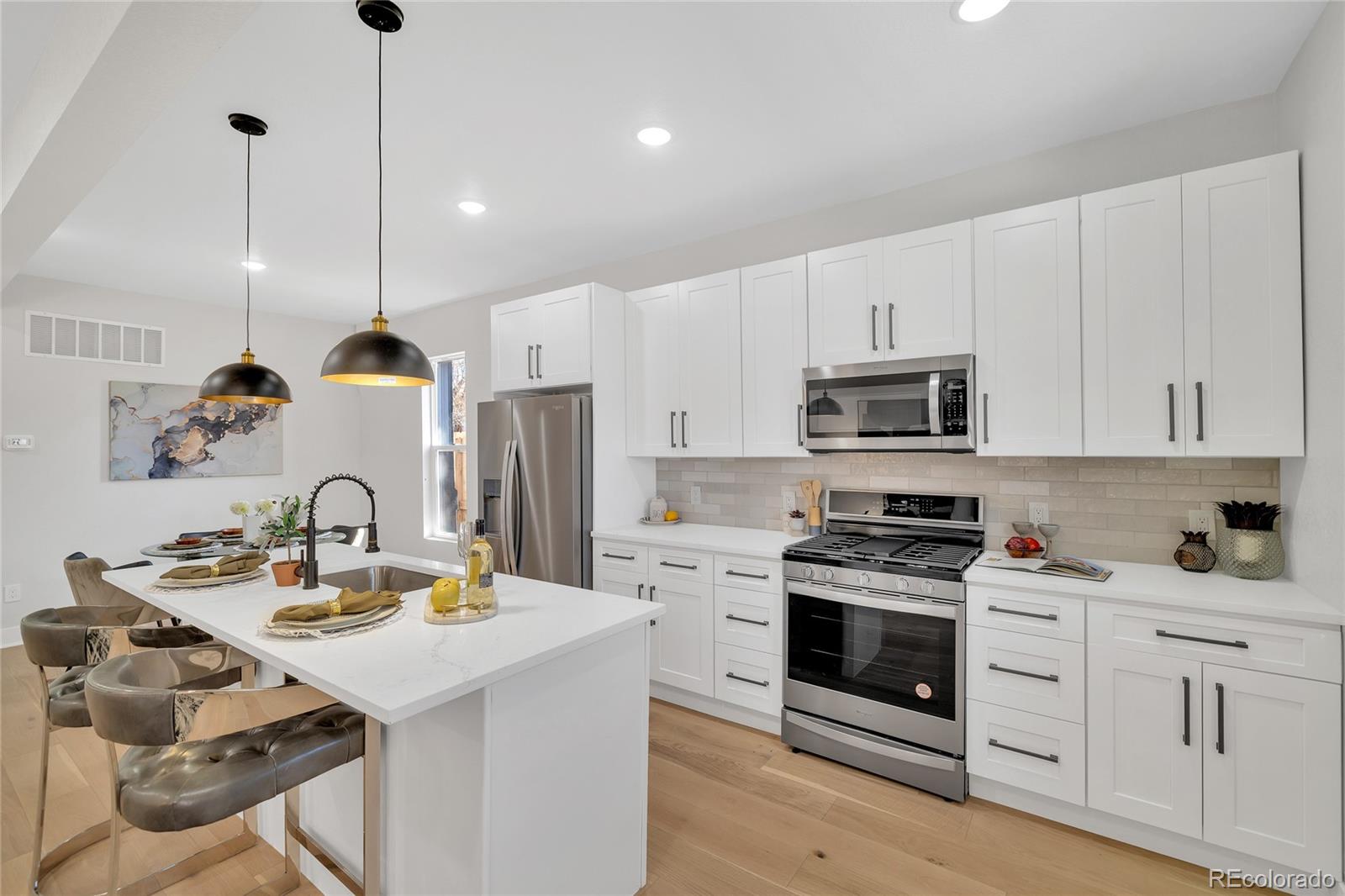 3512 High Street Denver, CO 80205 - Photo 10 of 33 a kitchen with white cabinets stainless steel appliances and sink
