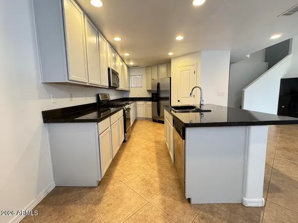a view of a kitchen with kitchen island granite countertop refrigerator and sink