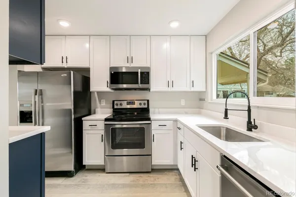 a kitchen with white cabinets appliances and a sink