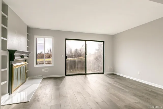 an empty room with wooden floor and windows