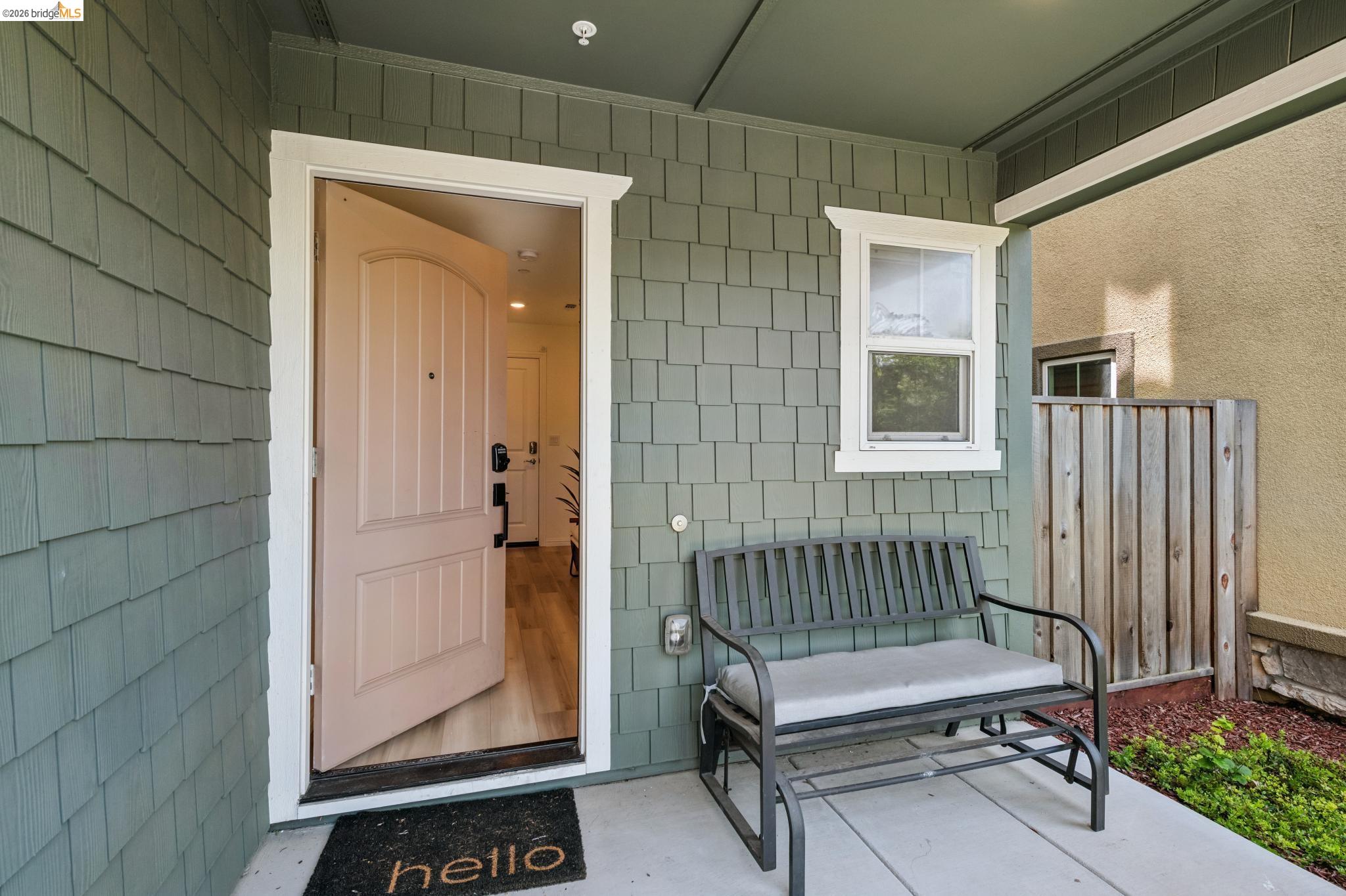 24157 Amaranth Loop Hayward, CA 94541 - Photo 5 of 63 Inviting covered entryway featuring shingle siding, a light-colored arched panel door with dark hardware, and a single-pane window