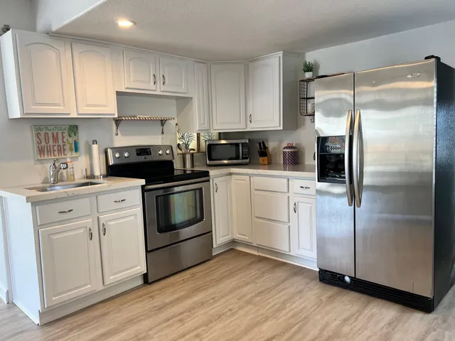 a kitchen with white cabinets stainless steel appliances and wooden floors