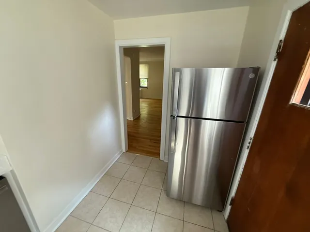 a view of a refrigerator in kitchen and an empty room