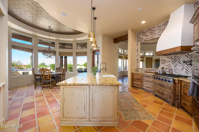 a dining hall with stainless steel appliances granite countertop a stove and white cabinets