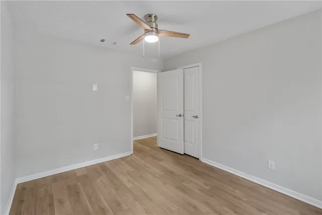 an empty room with windows and ceiling fan