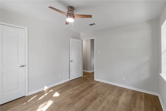an empty room with wooden floor chandelier and windows