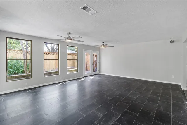 an empty room with wooden floor chandelier fan and windows
