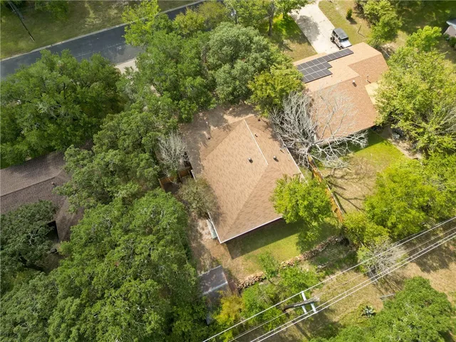 an aerial view of residential house with pool and trees all around