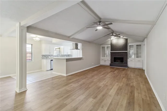 a view of empty room with kitchen and fireplace