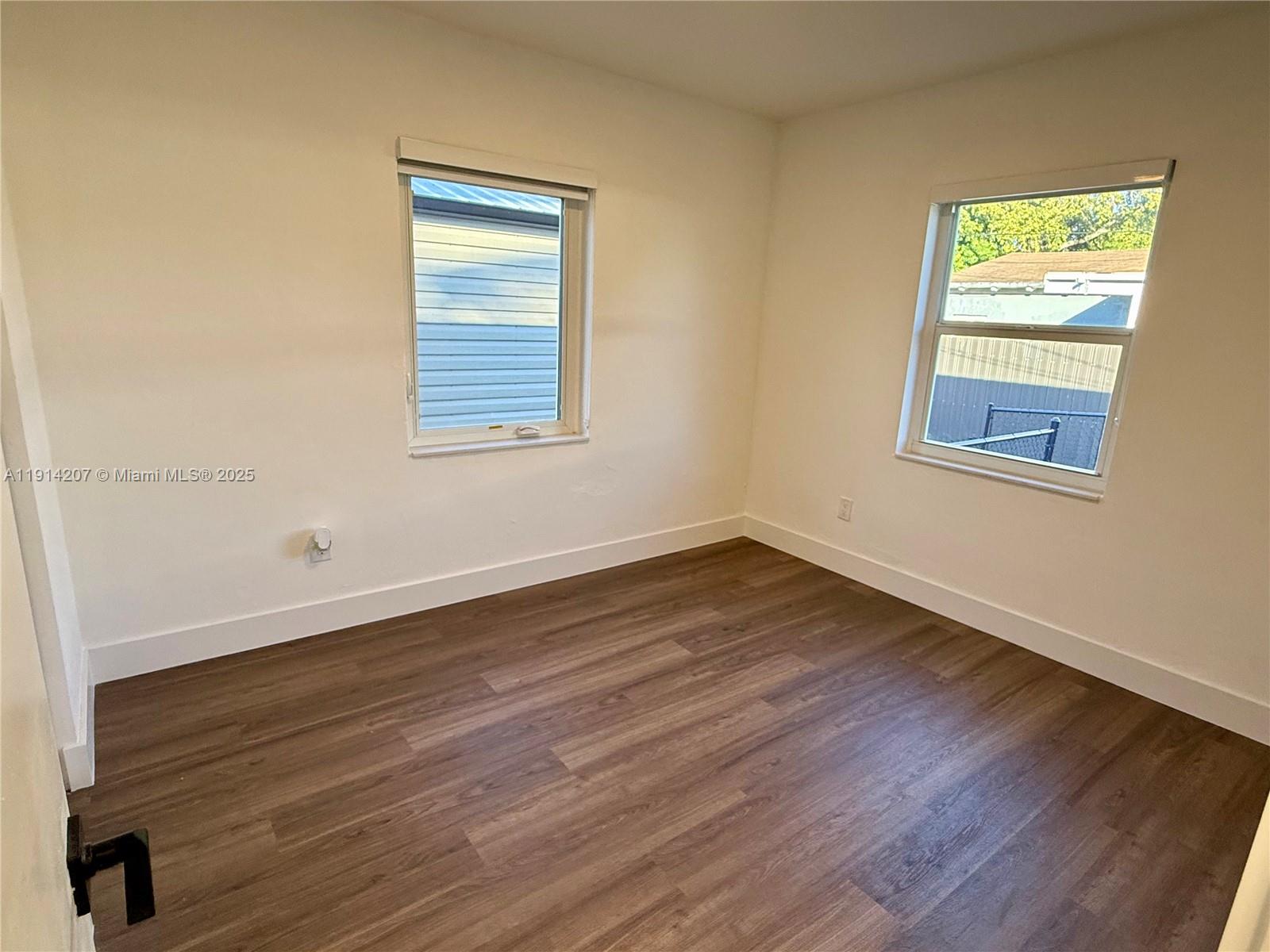 117 Northwest 118th Street, Unit 117 Miami, FL 33168 - Photo 14 of 20 a view of an empty room with wooden floor and a window