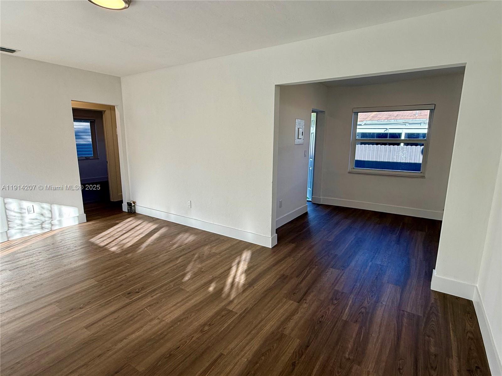 117 Northwest 118th Street, Unit 117 Miami, FL 33168 - Photo 5 of 20 an empty room with wooden floor and windows