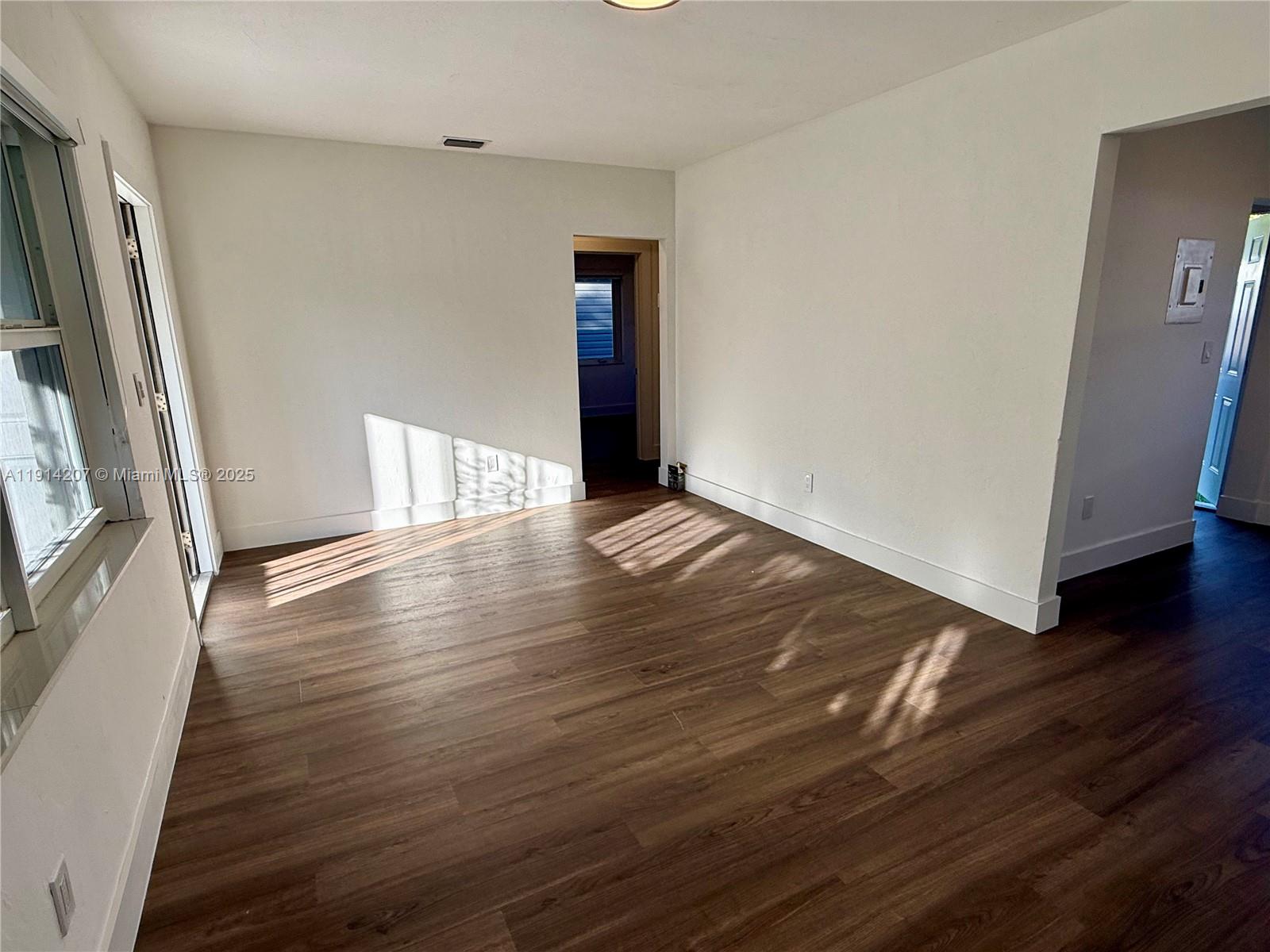 117 Northwest 118th Street, Unit 117 Miami, FL 33168 - Photo 6 of 20 a view of an empty room with wooden floor and a window