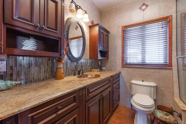 a bathroom with a granite countertop toilet sink and mirror